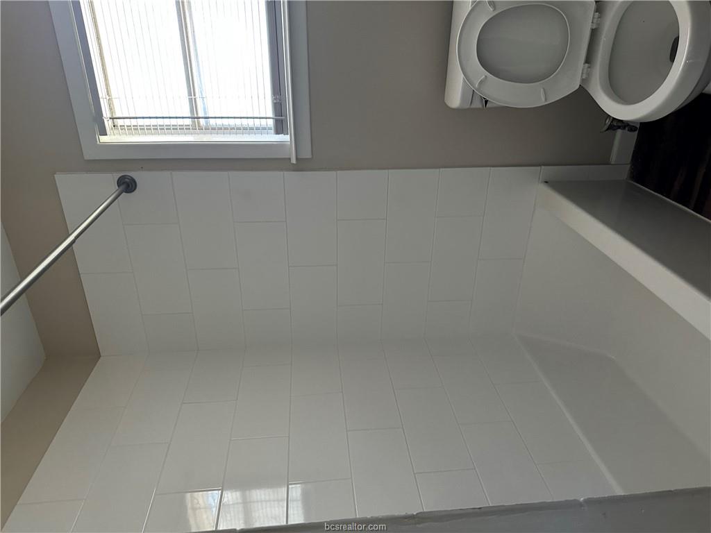 4005 College Main Street Bryan, TX 77801 - Photo 12 of 18 a white toilet sitting next to a bath tub