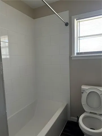 a white toilet sitting next to a bath tub