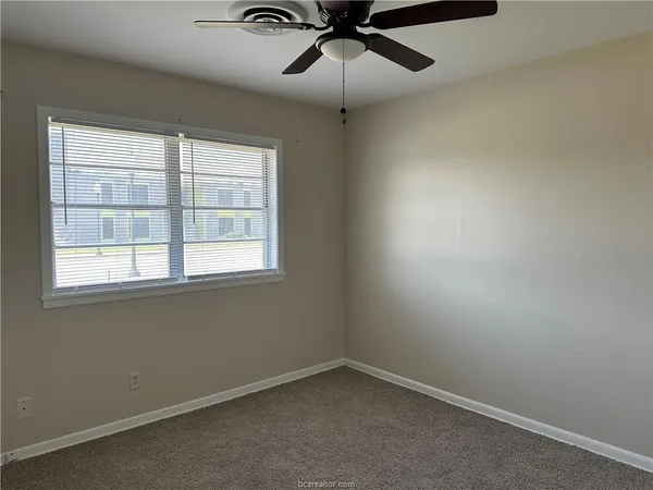 an empty room with a window and a fan