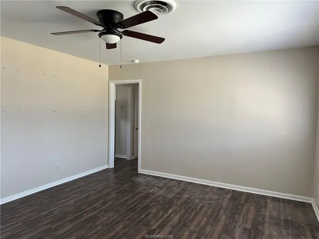an empty room with wooden floor ceiling fan and window