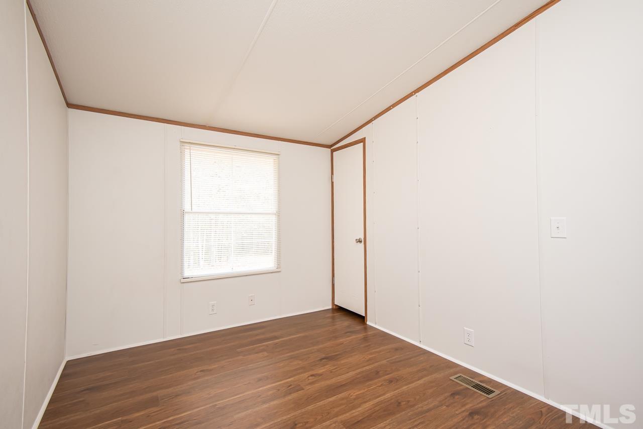 1545 Cheves Road Zebulon, NC 27597 - Photo 11 of 28 a view of an empty room with wooden floor and a window