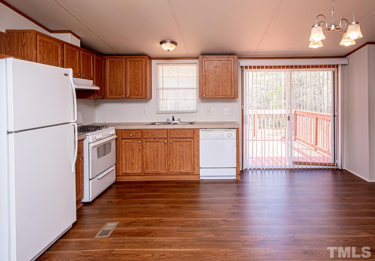 1545 Cheves Road Zebulon, NC 27597 - Photo 13 of 28 a kitchen with a refrigerator a sink and dishwasher with wooden floor