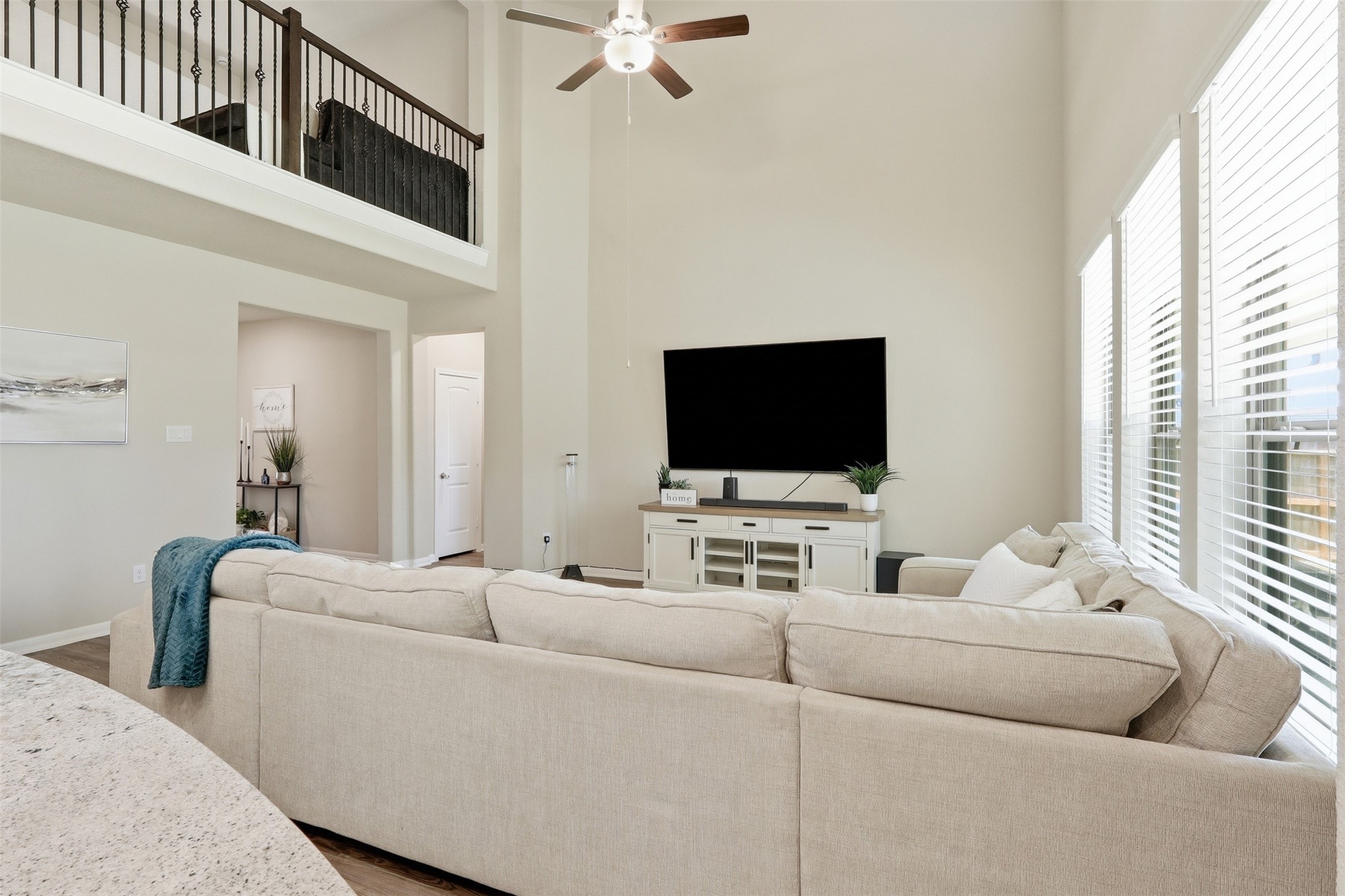 6310 Fawn Path Drive Conroe, TX 77303 - Photo 13 of 41 Bright and airy living room featuring soaring ceilings, expansive windows, and an open view to the upstairs game room, creating a spacious and inviting atmosphere.