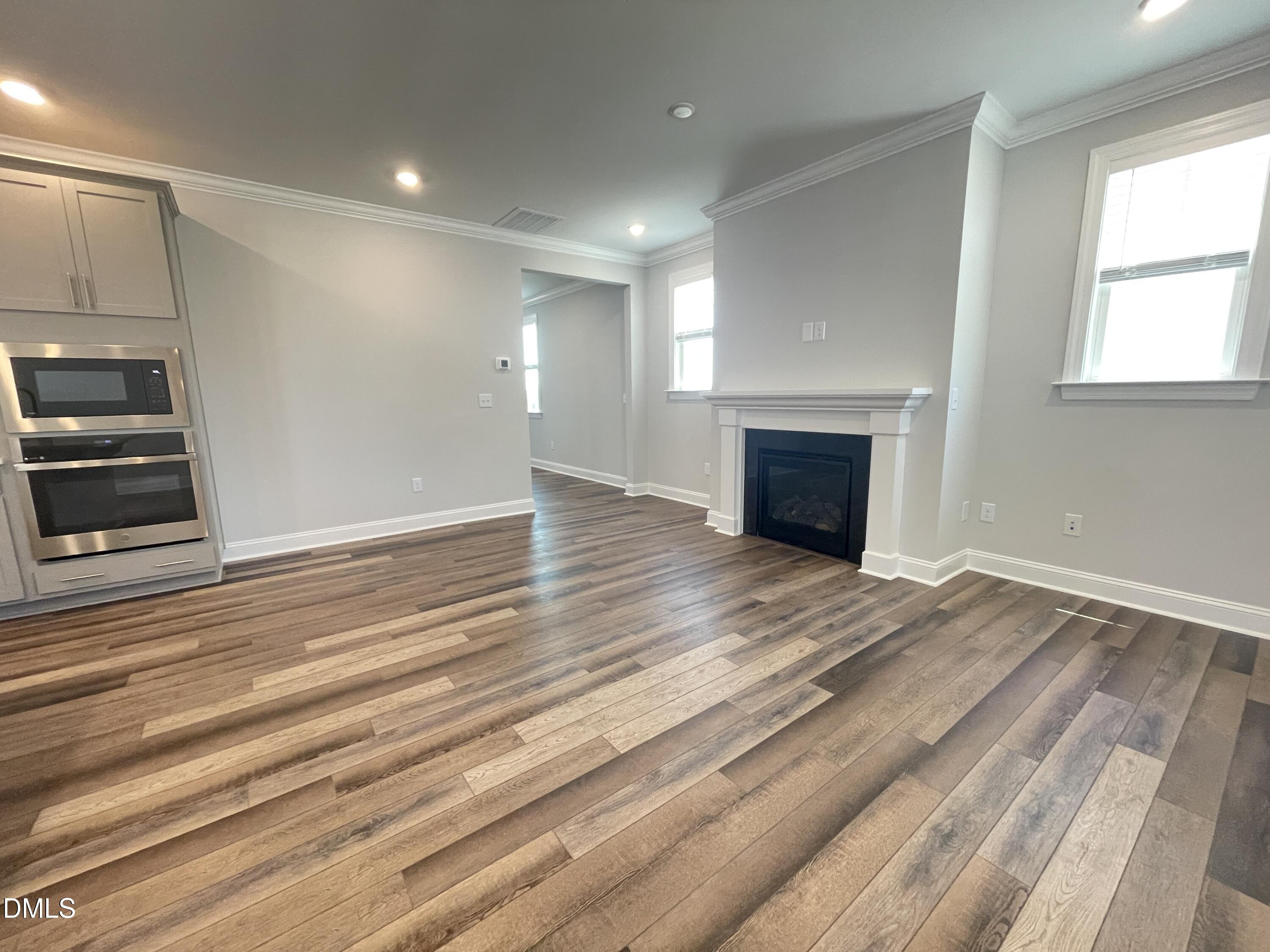 152 Baymouth Lane Raleigh, NC 27610 - Photo 5 of 34 an empty room with wooden floor fireplace and windows