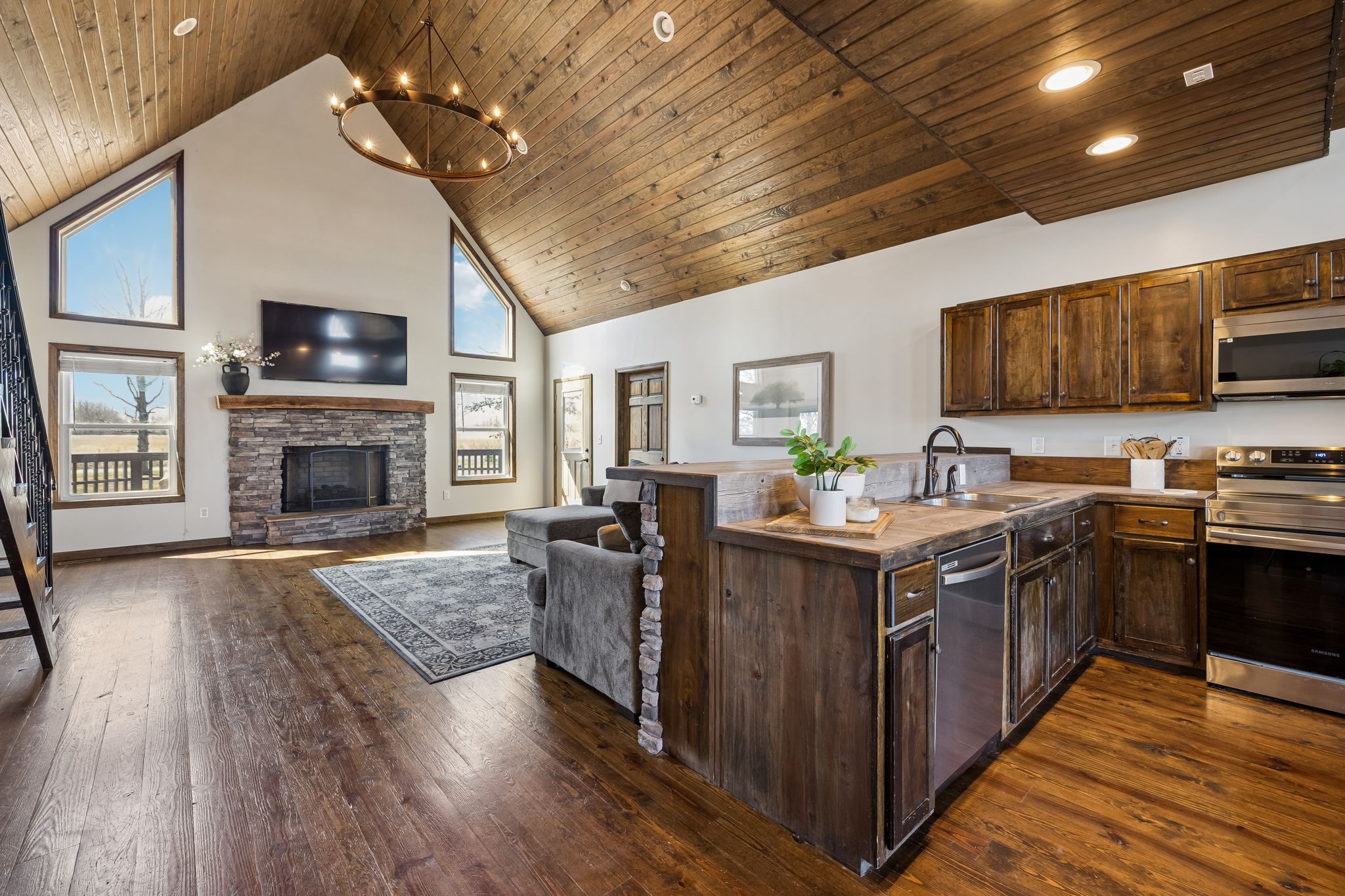 a kitchen with kitchen island granite countertop a stove top oven a sink dishwasher a dining table and chairs with wooden floor