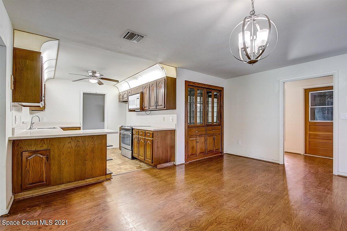 805 Knecht Road Northeast Palm Bay, FL 32905 - Photo 13 of 42 a view of a kitchen with stainless steel appliances granite countertop a stove top oven a sink with wooden floor and cabinets
