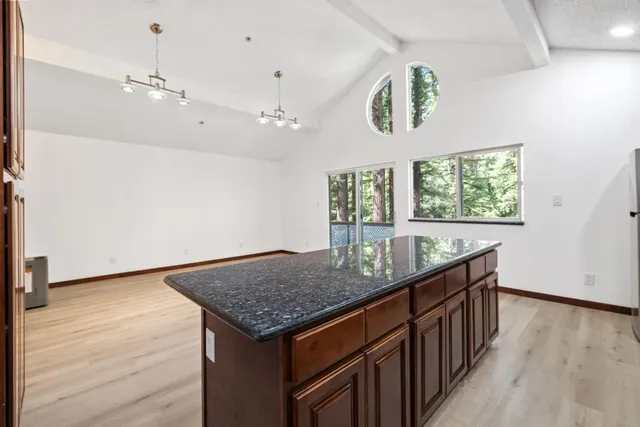 a kitchen with stainless steel appliances granite countertop a sink dishwasher a refrigerator and a stove with wooden floor