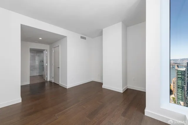 an empty room with wooden floor & windows
