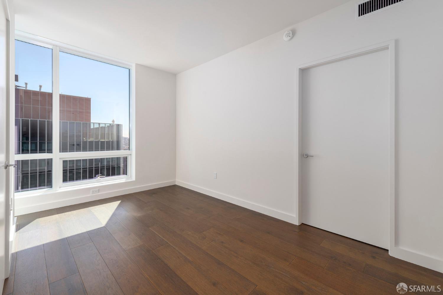 488 Folsom Street, Unit 4305 San Francisco, CA 94105 - Photo 10 of 45 a view of an empty room with wooden floor and a window