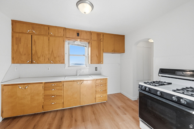 708 9th Street Ogden, UT 84404 - Photo 10 of 17 Kitchen with range with gas cooktop, light countertops, arched walkways, light wood finished floors, and wood finish cabinets