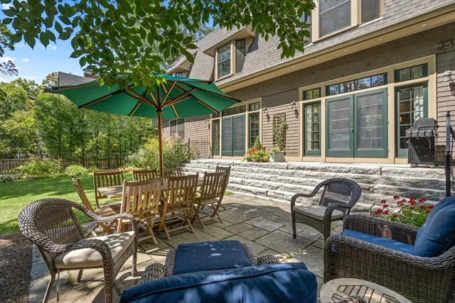 a view of a patio with couches table and chairs under an umbrella with a barbeque