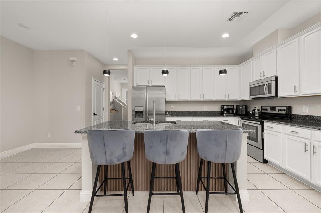 12333 Via Derna Place Windermere, FL 34786 - Photo 16 of 56 a kitchen with stainless steel appliances granite countertop a sink a stove a refrigerator a center island and chairs