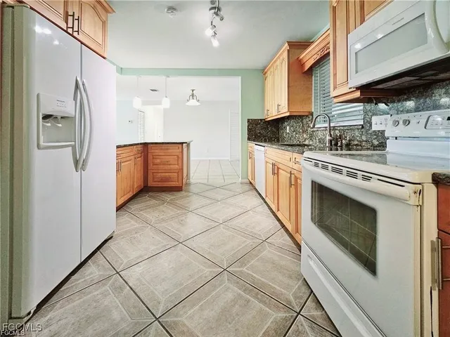 a kitchen with stainless steel appliances granite countertop a refrigerator a stove and a sink