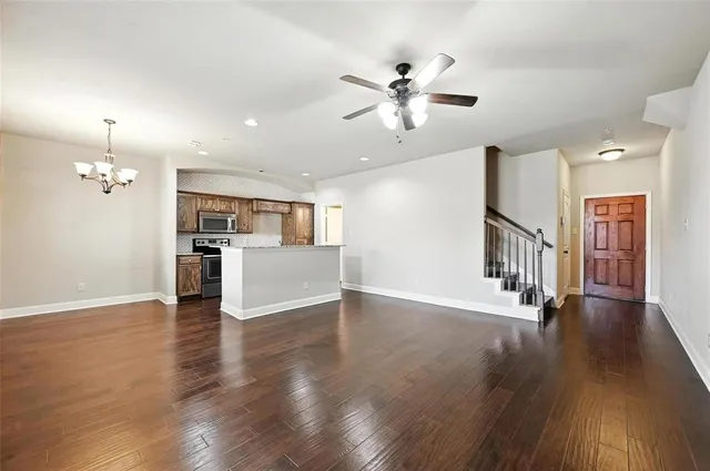 a view of an empty room with wooden floor and a kitchen