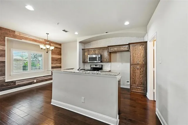 a kitchen with stainless steel appliances granite countertop a stove a refrigerator a sink and a oven with wooden floor