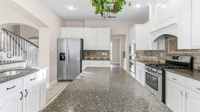 a large kitchen with stainless steel appliances kitchen island granite countertop a refrigerator and a stove top oven