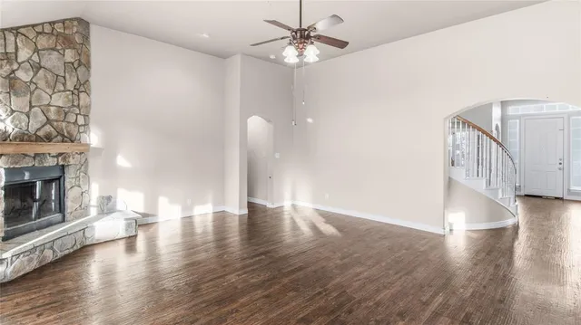 a view of an empty room with wooden floor and a fireplace