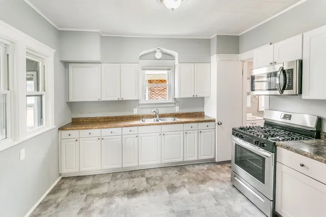 a kitchen with granite countertop a sink stove top oven and cabinets
