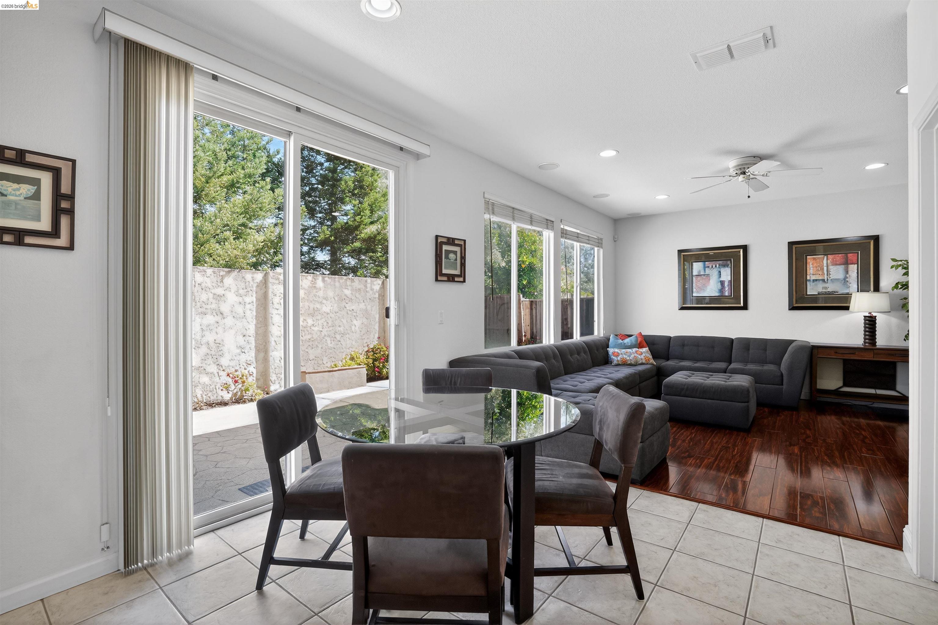 1221 Andrea Way Vallejo, CA 94591 - Photo 12 of 29 Open-concept living space with a dining area featuring light-toned tile flooring, a glass-top table, and direct access to an outdoor patio through sliding glass doors