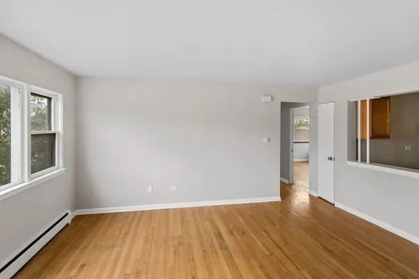 a view of an empty room with wooden floor and a window