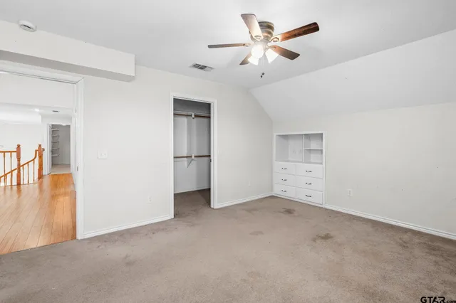 an empty room with closet and a ceiling fan
