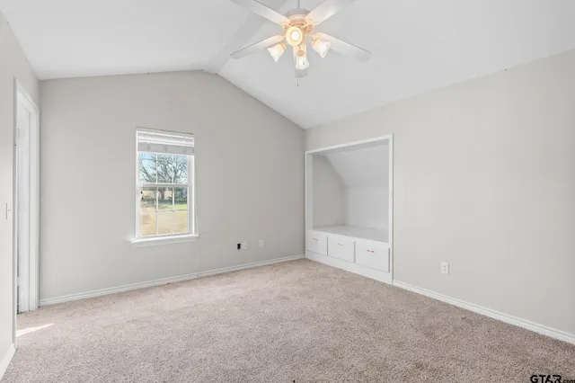 an empty room with a chandelier fan and windows