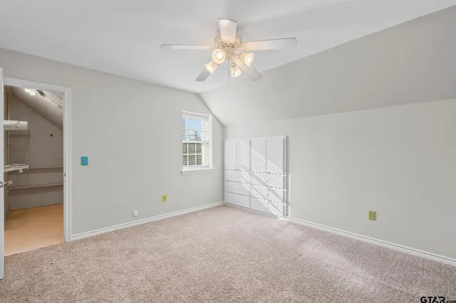 an empty room with chandelier fan and windows