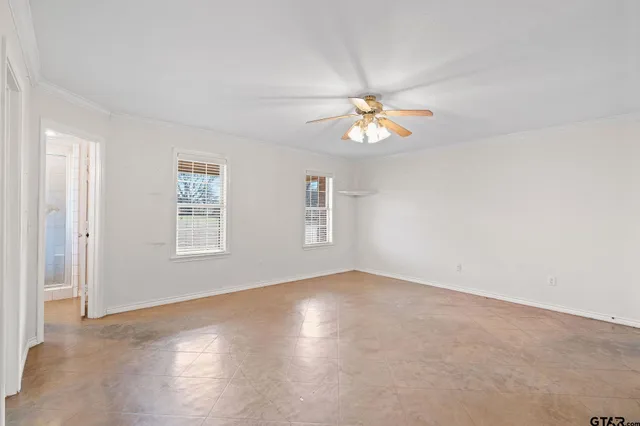 an empty room with windows and fan