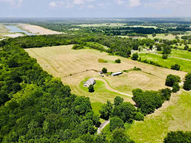 an aerial view of a residential houses with outdoor space and trees all around