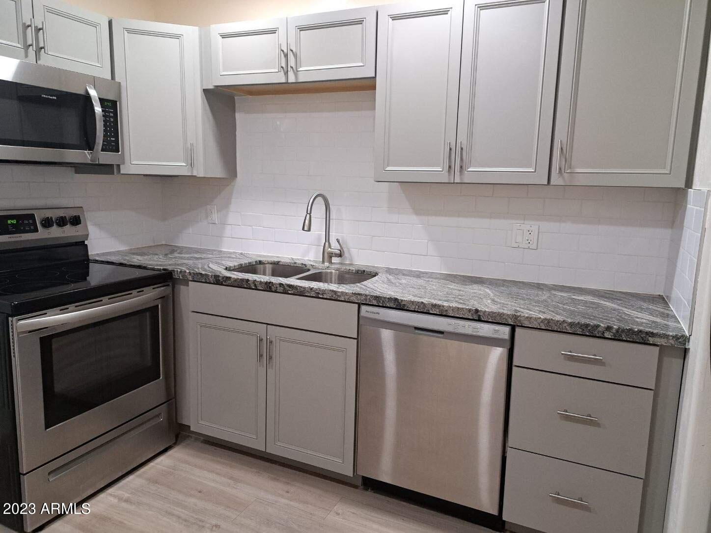 6713 East Cheery Lynn Road, Unit 4 Scottsdale, AZ 85251 - Photo 6 of 12 a kitchen with granite countertop white cabinets and stainless steel appliances