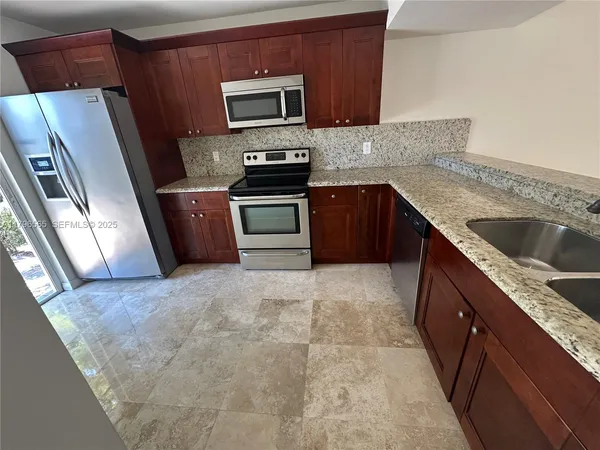 a kitchen with granite countertop a refrigerator and a sink
