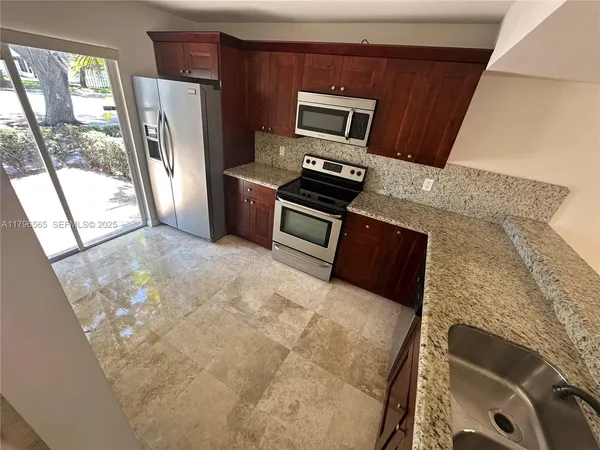 a kitchen with stainless steel appliances kitchen island granite countertop a refrigerator stove and sink