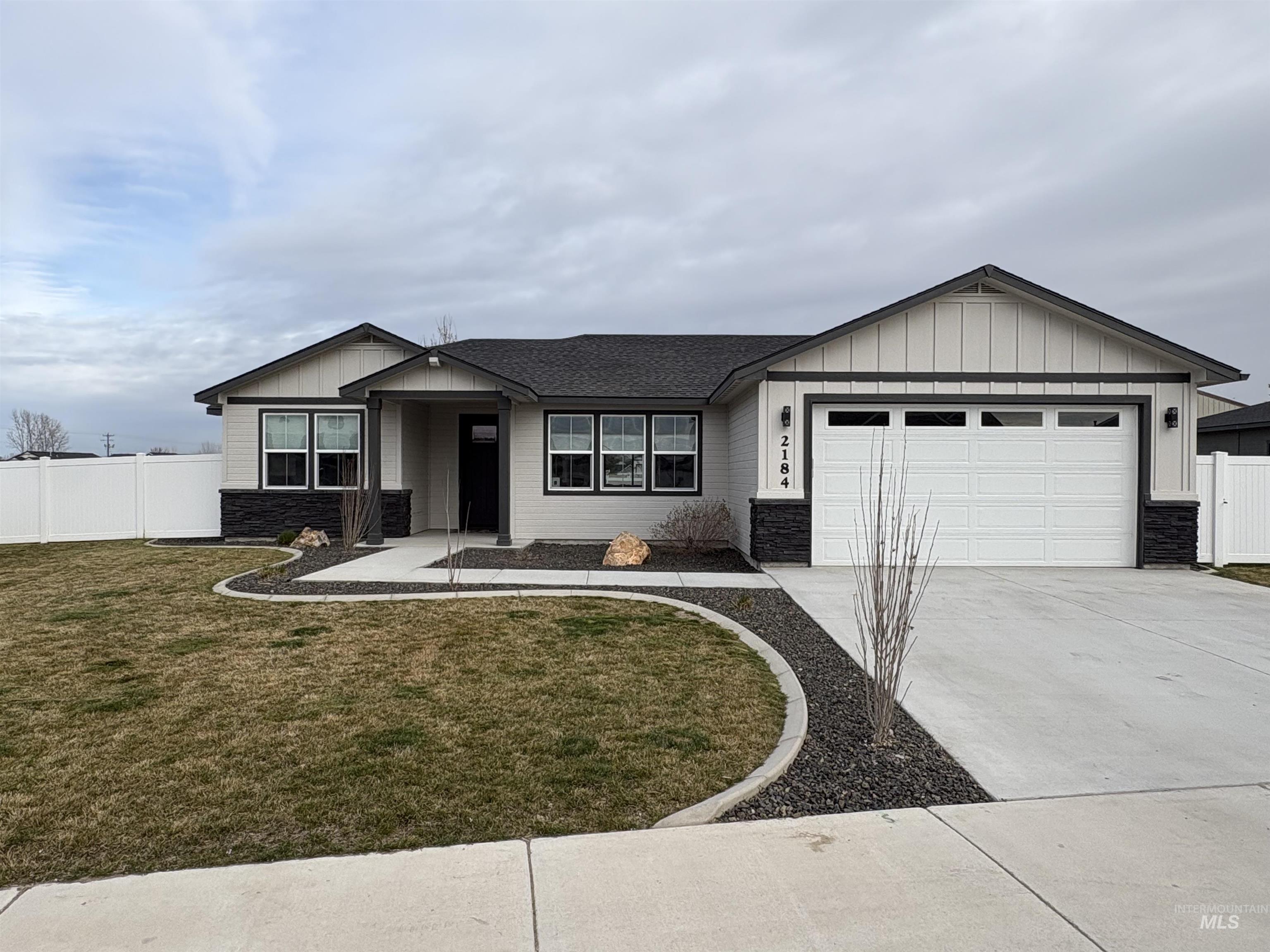 2184 Austin Way Fruitland, ID 83619 - Photo 2 of 34 Ranch-style house with stone siding, concrete driveway, board and batten siding, and an attached garage