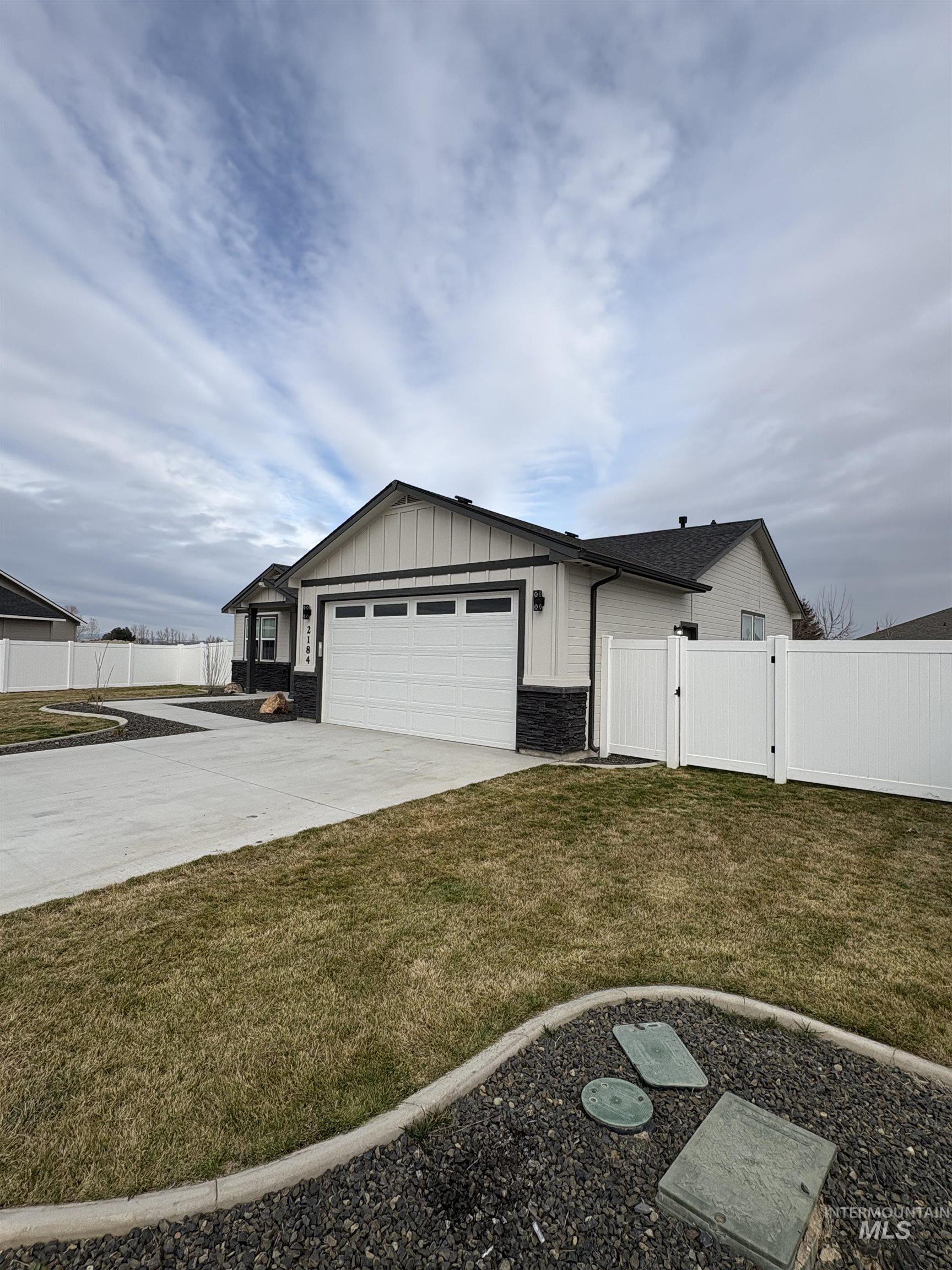 2184 Austin Way Fruitland, ID 83619 - Photo 6 of 34 Ranch-style home featuring a gate, board and batten siding, stone siding, an attached garage, and concrete driveway