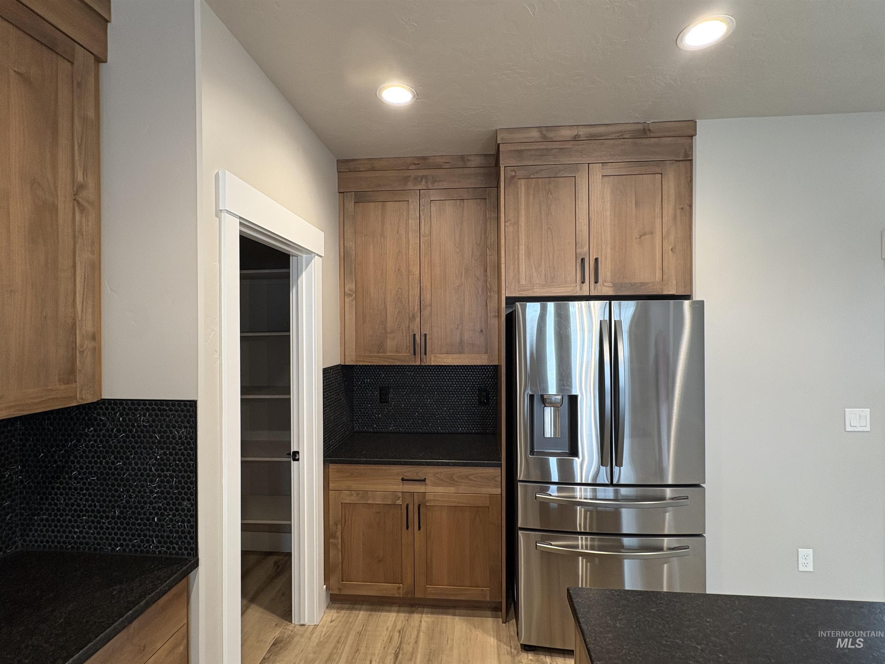 2184 Austin Way Fruitland, ID 83619 - Photo 9 of 34 Kitchen featuring stainless steel refrigerator with ice dispenser, tasteful backsplash, wood finish cabinetry, dark stone countertops, and recessed lighting