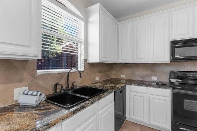 a kitchen with granite countertop white cabinets and a stove