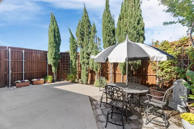 a view of a patio with a table and chairs under an umbrella with a small yard