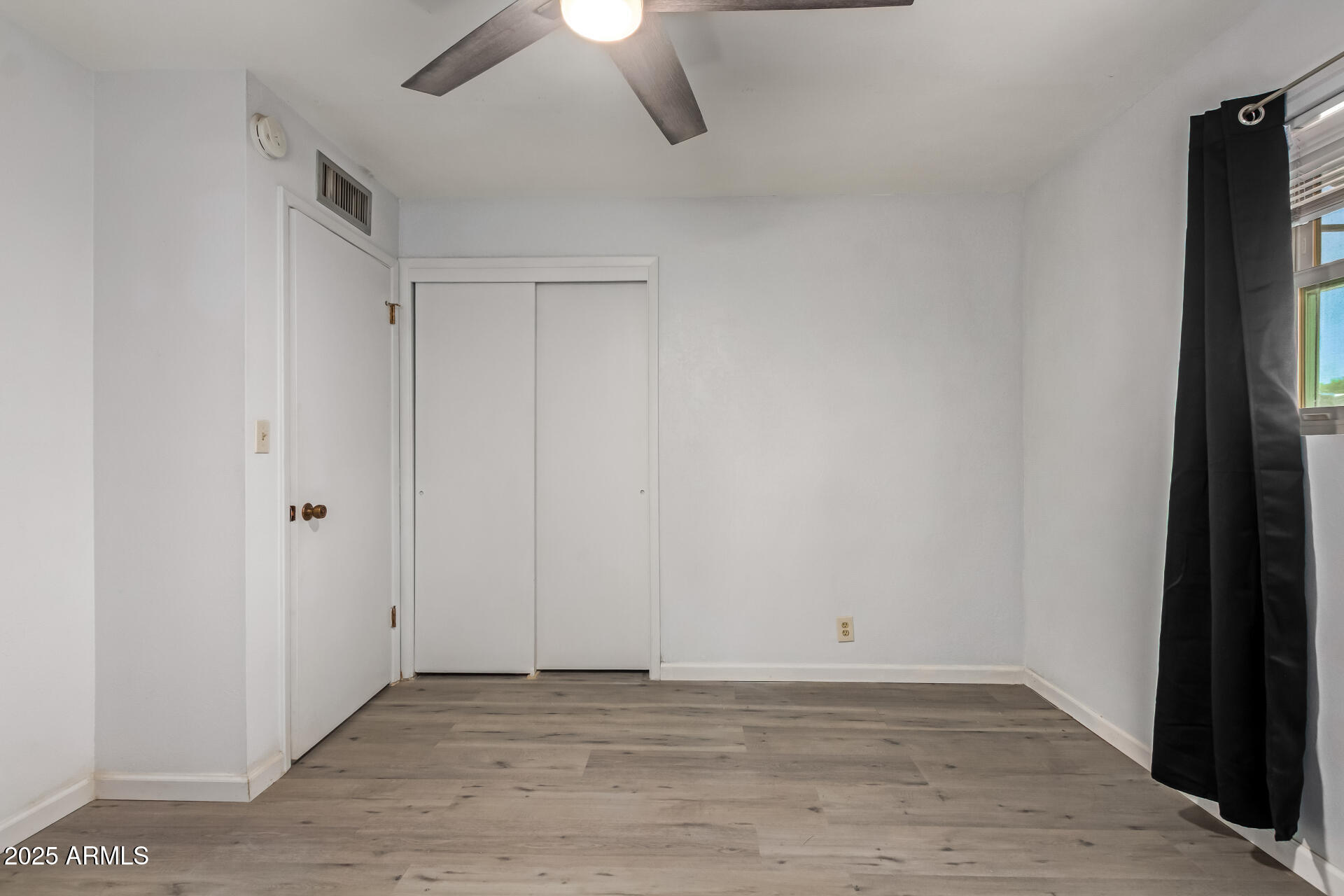 6149 East Decatur Street Mesa, AZ 85205 - Photo 18 of 24 a view of an empty room with wooden floor and a ceiling fan