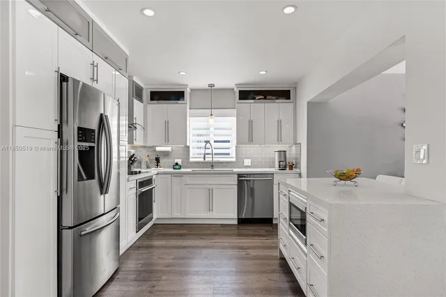 a kitchen with a sink a refrigerator and white cabinets