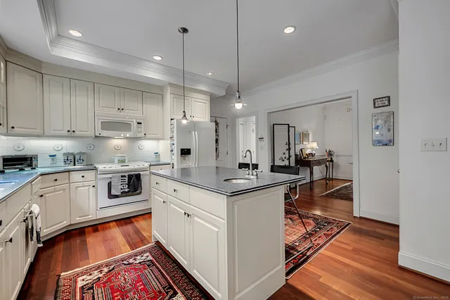 a open kitchen with stainless steel appliances granite countertop a stove and white cabinets