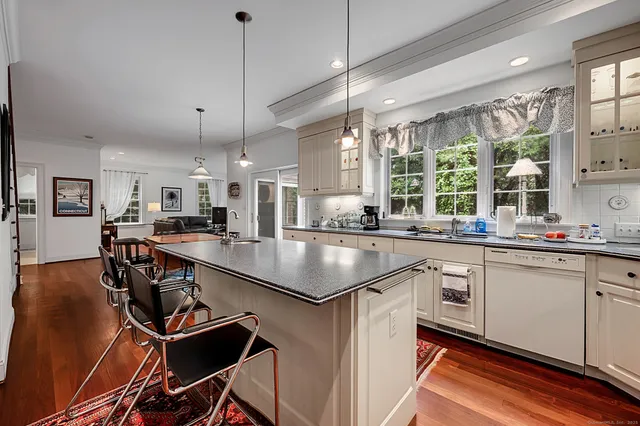 a kitchen with stainless steel appliances granite countertop sink stove and white cabinets with wooden floor