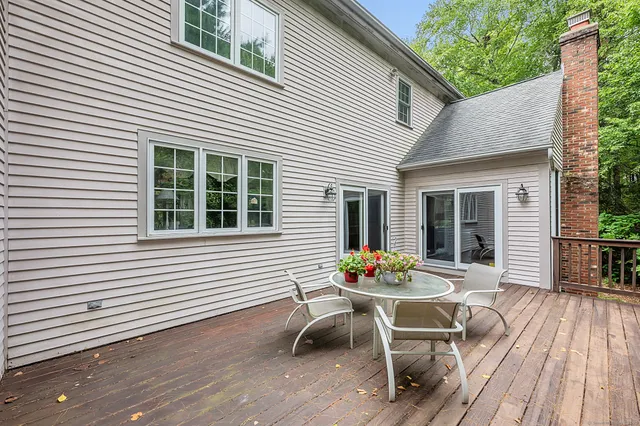 a backyard of a house with wooden chairs and a barbeque