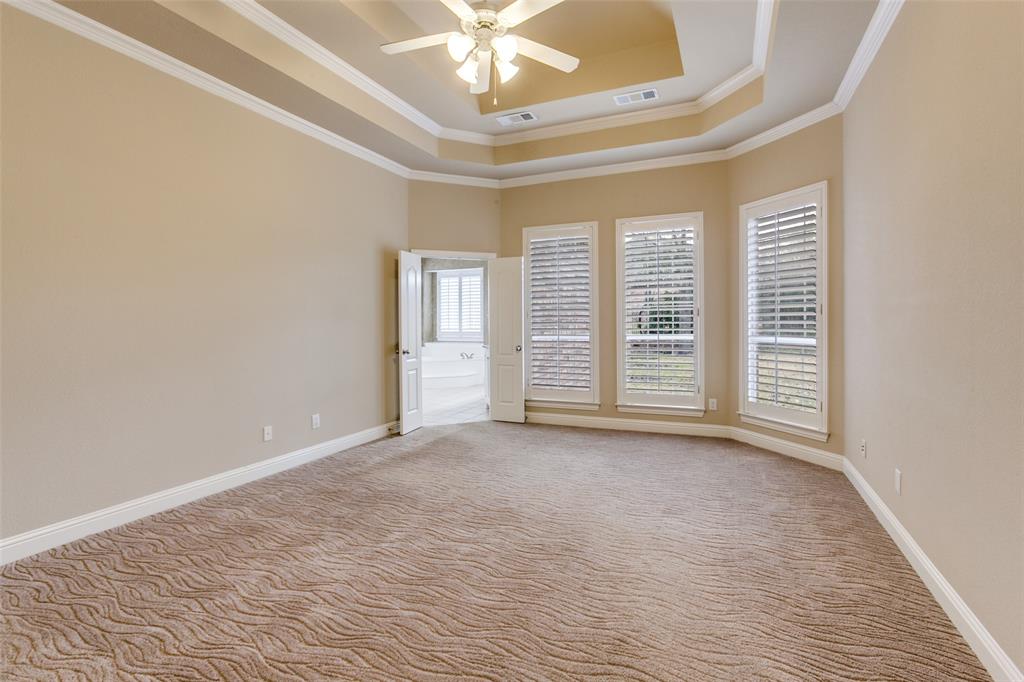 6027 Rathbone Drive Parker, TX 75002 - Photo 17 of 39 Huge primary bedroom with a raised trey ceiling, ornamental molding, and bay window looking into the spacious backyard.