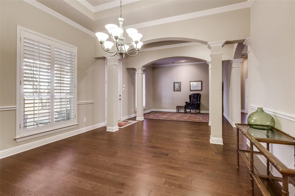 6027 Rathbone Drive Parker, TX 75002 - Photo 6 of 39 Formal dining space with ornate columns, arched walkways, crown molding, dark wood flooring, and a chandelier.