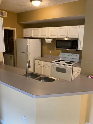 a kitchen with kitchen island a sink a stove and refrigerator