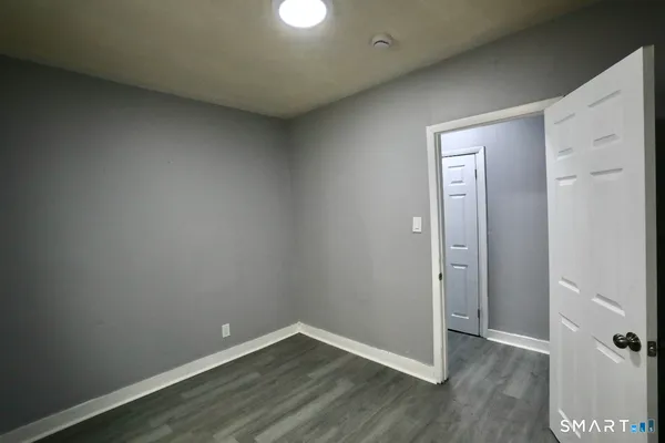 a view of an empty room with wooden floor and closet