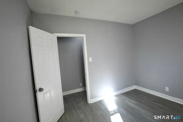 an empty room with wooden floor and entrance