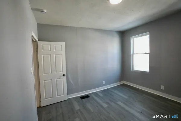 an empty room with wooden floor closet and windows