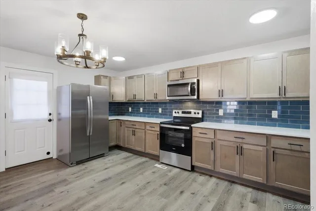 a kitchen with stainless steel appliances granite countertop a refrigerator a sink dishwasher a stove and white cabinets with wooden floor