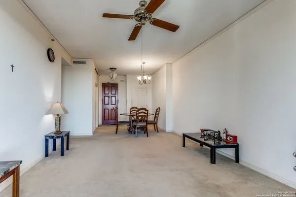 an empty room with furniture and a chandelier fan